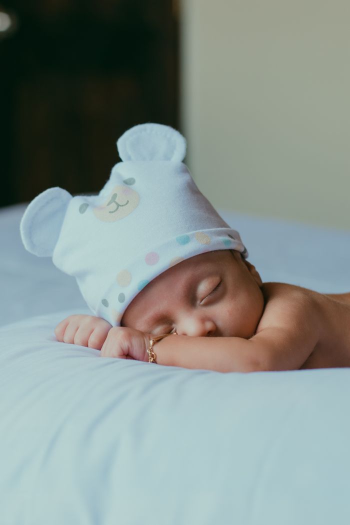 Adorable baby sleeping peacefully in a cute bear-themed hat, capturing innocence and calmness.